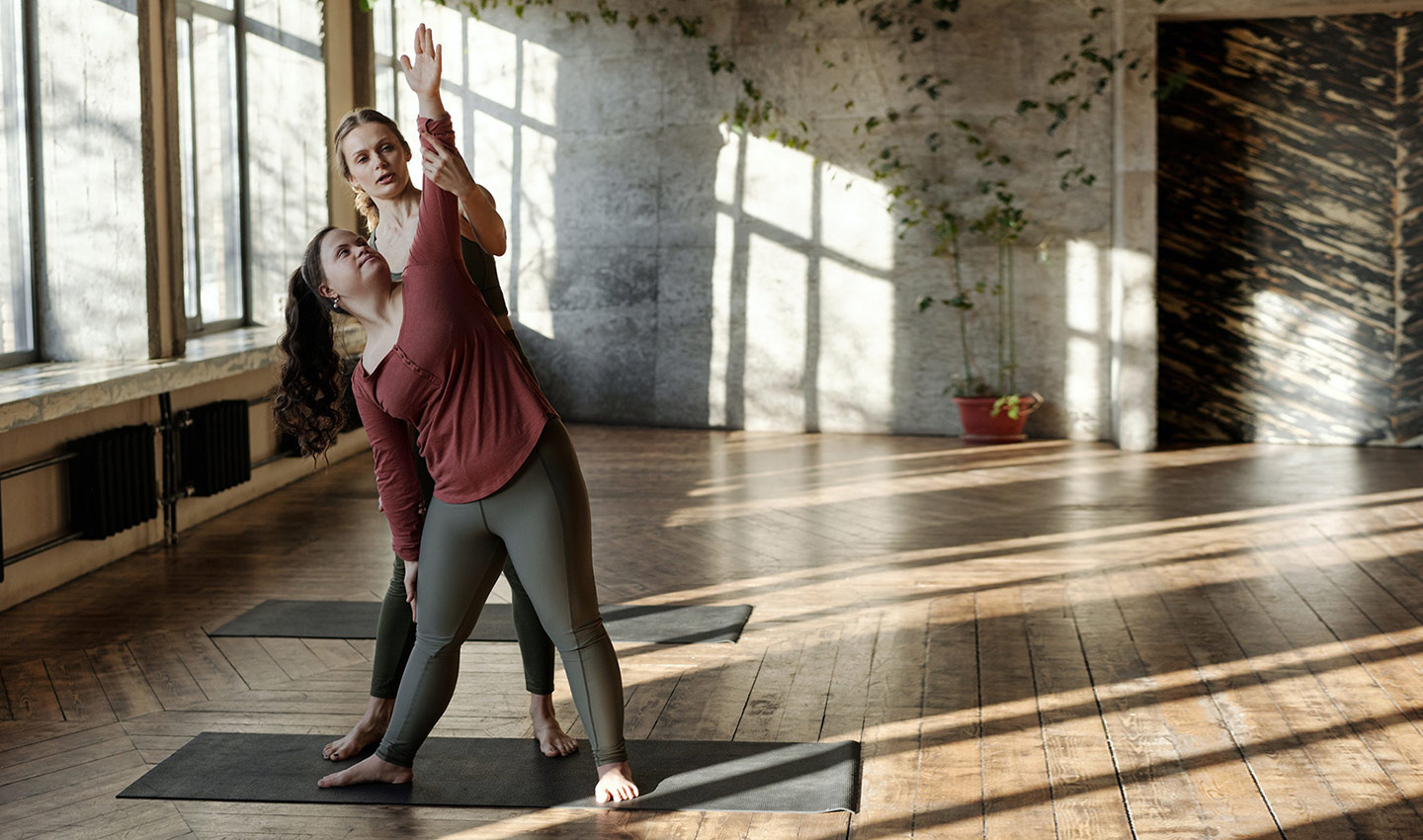 Eine Yogalehrerin hilft ihrer Schülerin, die Haltung einer Yoga-Pose zu verbessern