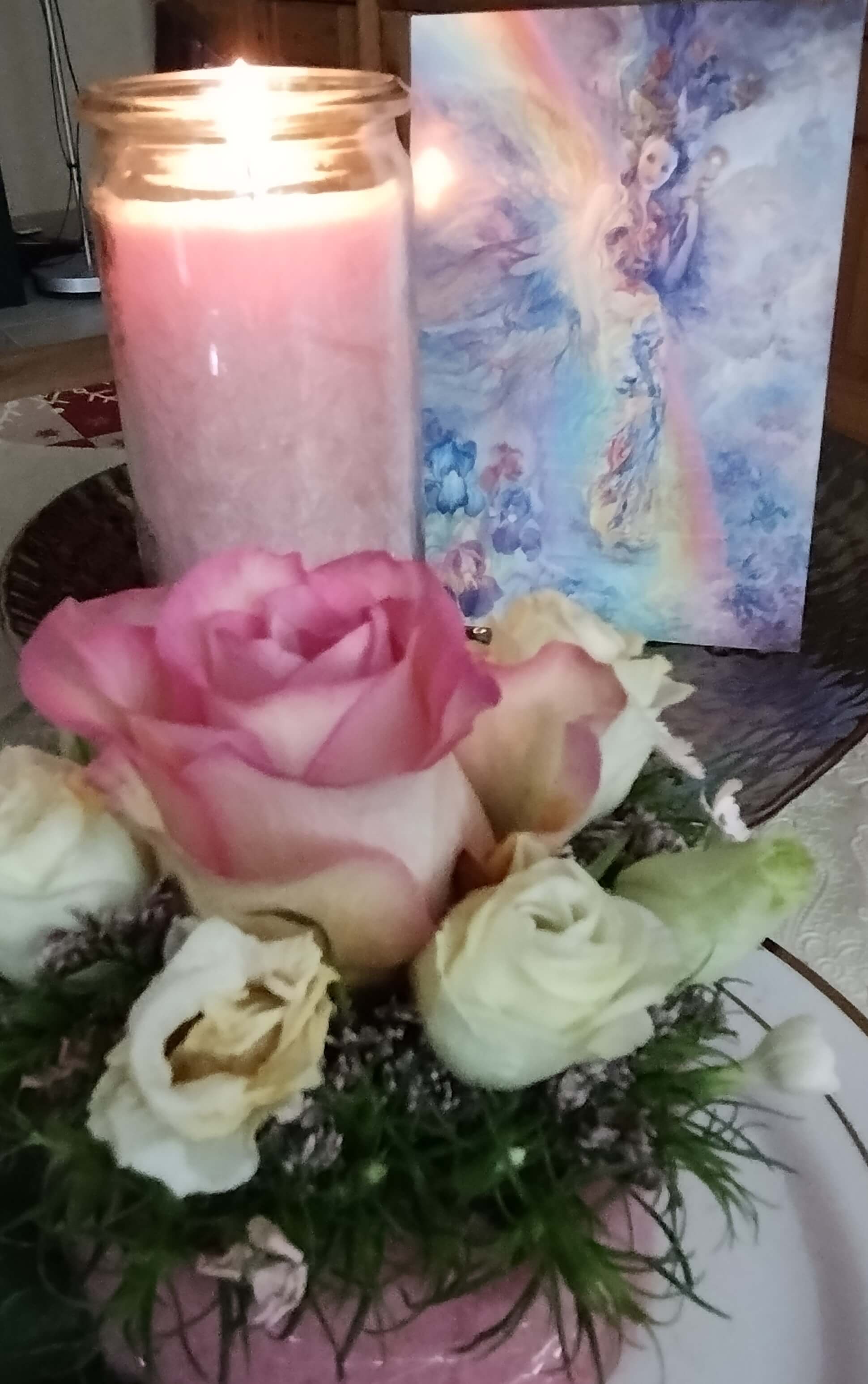 Brennende Kerze hinter einem Rosengesteck, daneben ein Bild von Josephine Wall, "Regenbogen-Iris"