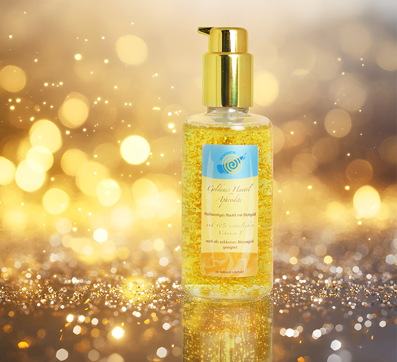 Eine durchsichtige Glasflasche mit goldenem Spenderkopf, gefüllt mit goldenem Hautöl und sichtbaren Goldpartikeln.