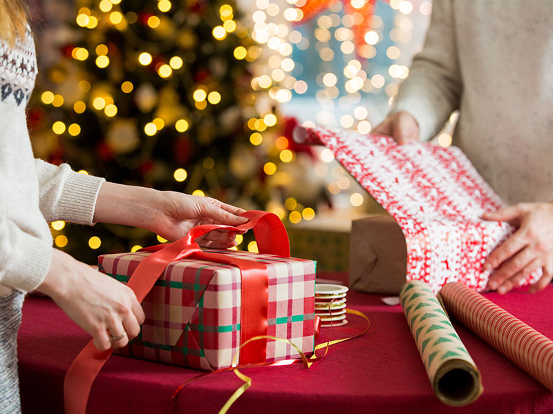 Ein Paar verpackt gemeinsam Weihnachtsgeschenke