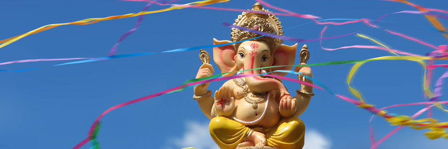 Ganesha-Statue vor blauem Himmel, umgeben von bunten Luftschlangen