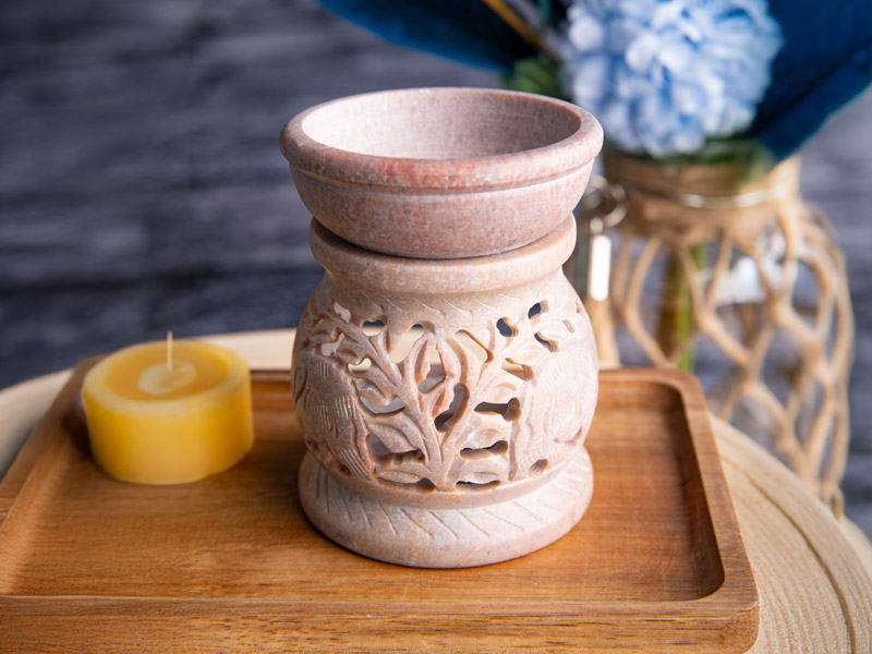 Eine Aromalampe auf einem Holztablett mit Kerze