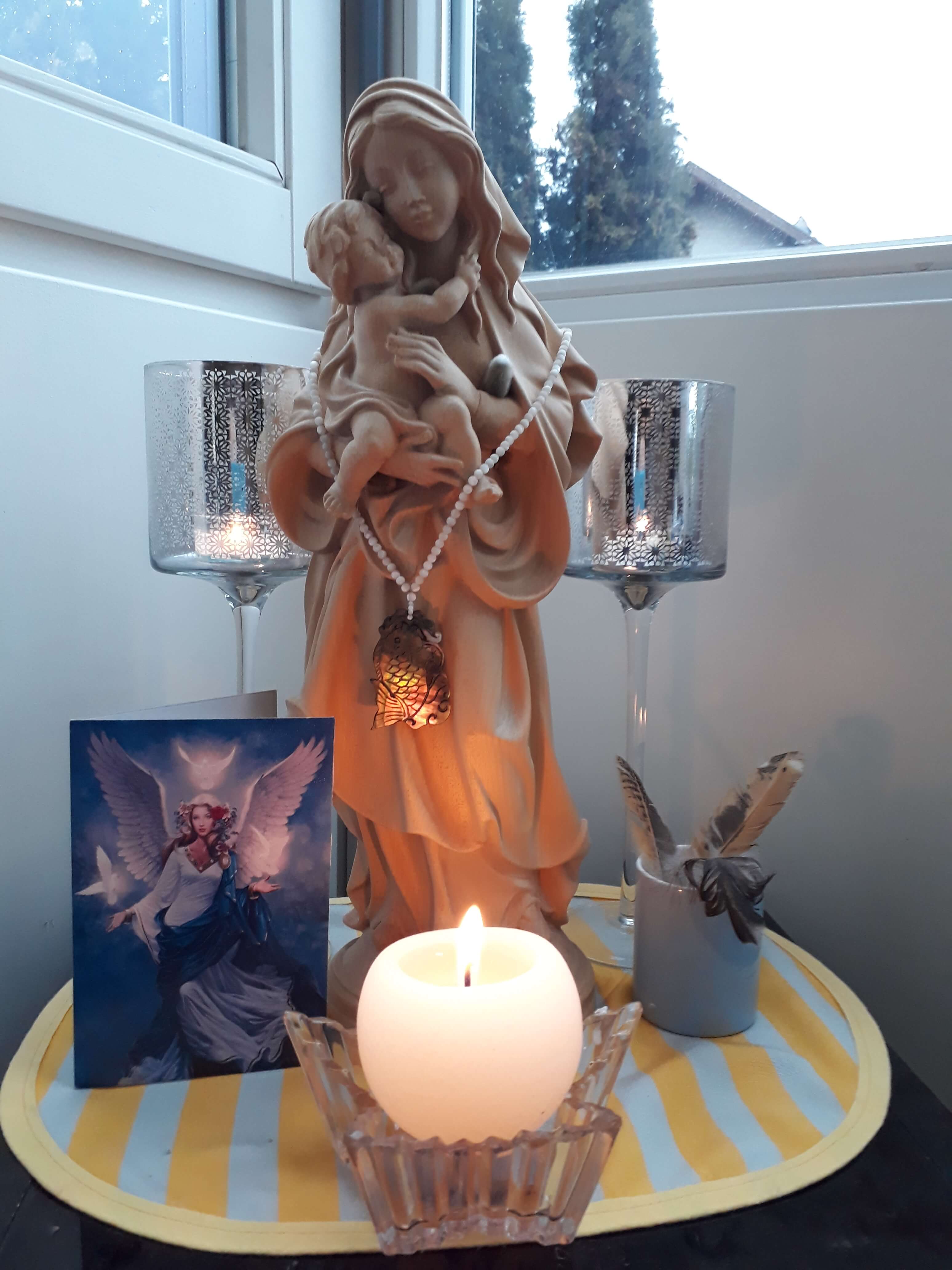 Brennende Kerze vor einer Marienfigur