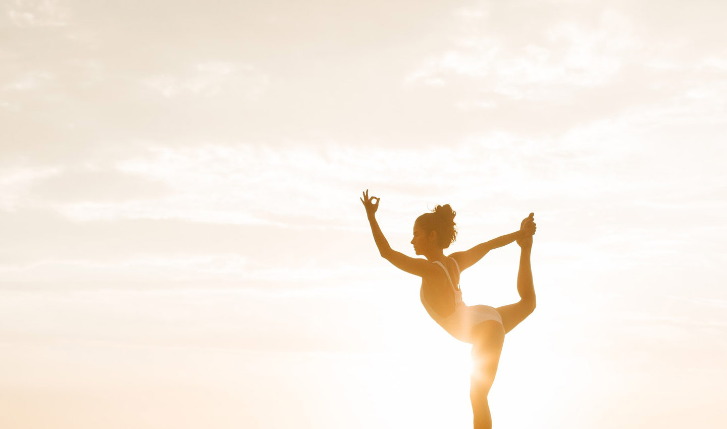 Eine Frau übt die Yoga-Pose "Der Tänzer" unter freiem Himmel