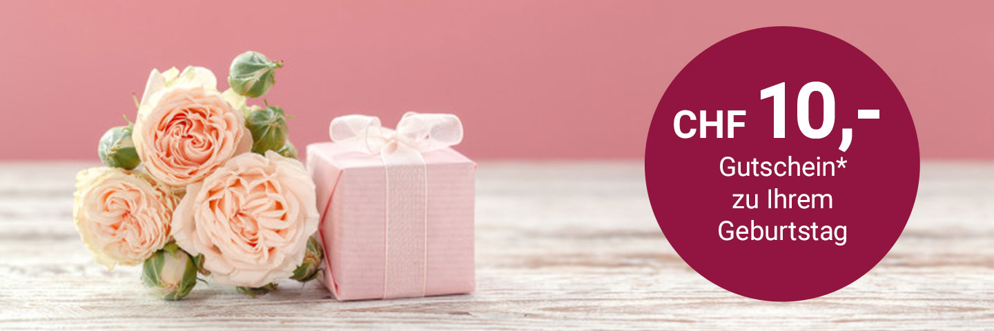 3 hellrosa Rosen liegen auf einem weißen Holztisch, daneben ein kleines, in rosa Papier eingepacktes Geschenk mit weißer Schleife. Rechts im Bild ein dunkelroter Kreis mit weißem Text: "CHF 10 Gutschein zu Ihrem Geburtstag"
