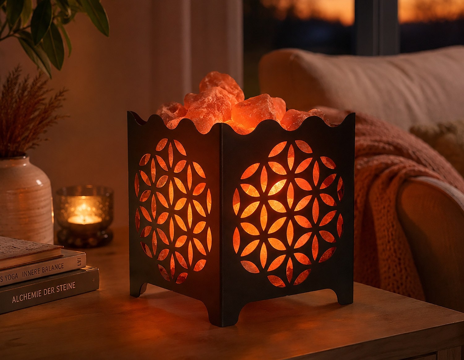 Eine leuchtende Salzlampe in einem schwarzen Metallhalter mit Blume-des-Lebens-Muster steht in einer gemütlich beleuchteten Wohnzimmerecke.