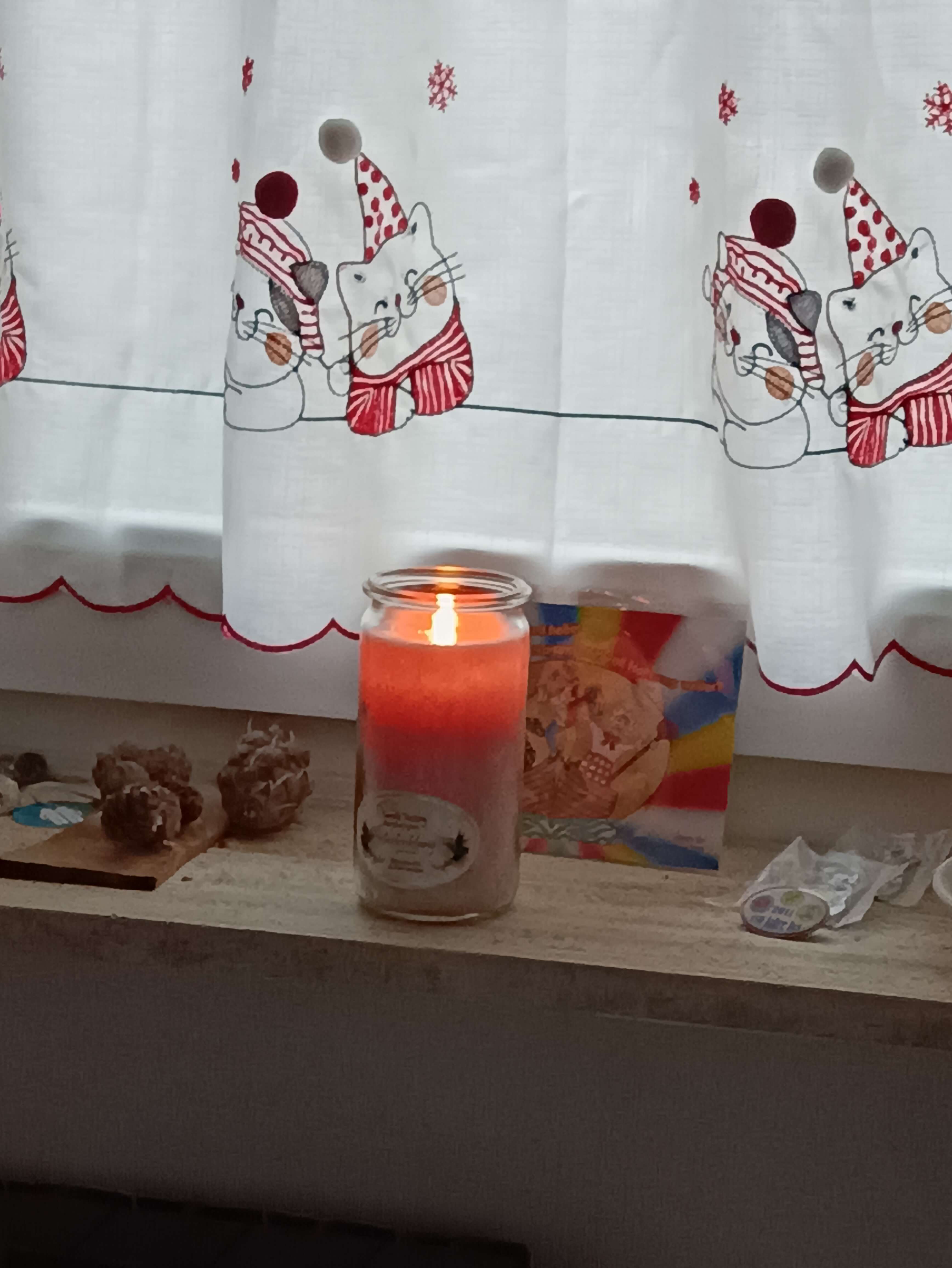 Brennende Kerze auf der Fensterbank vor einer Postkarte
